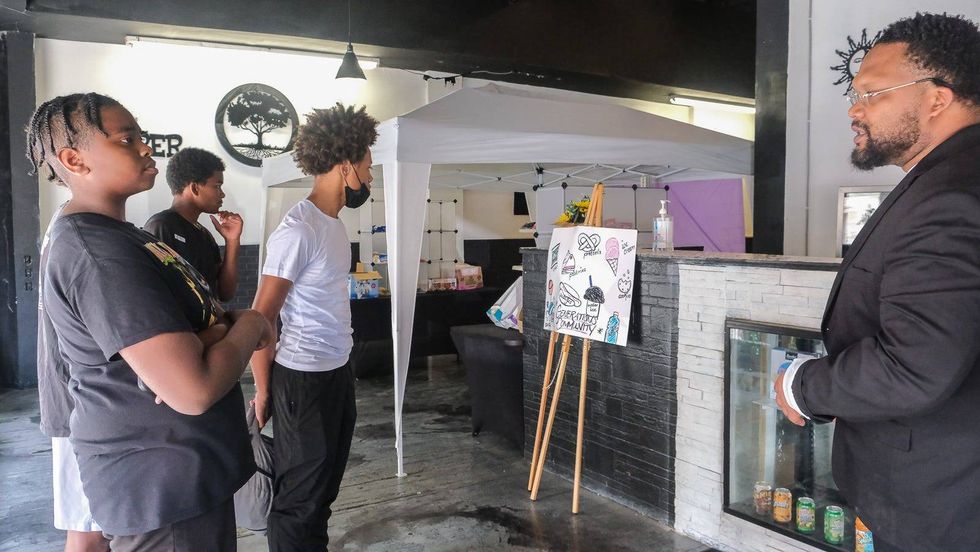 Tyce Combs stands with young men at Generations Community Square, the community-focused part of his barber shop academy in Upper Darby.