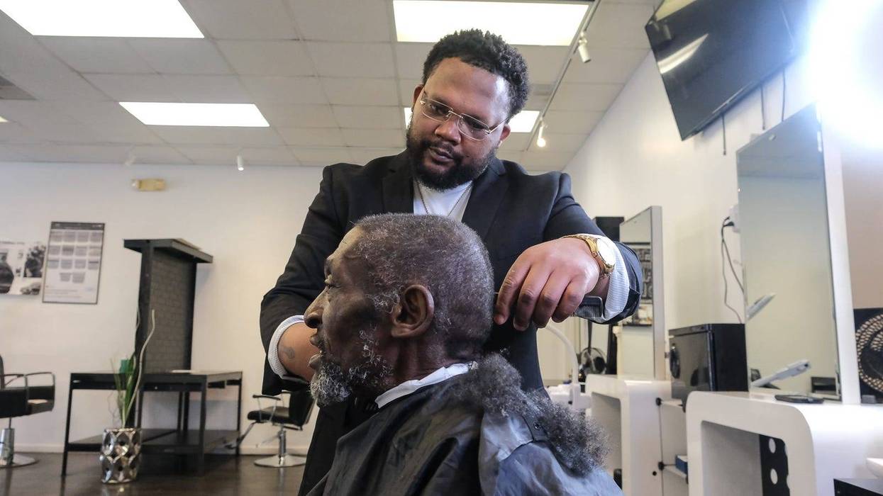 Tyce Combs works with client Yahya Muhammad, who has been coming to the school for more than 15 years to get his hair cut.