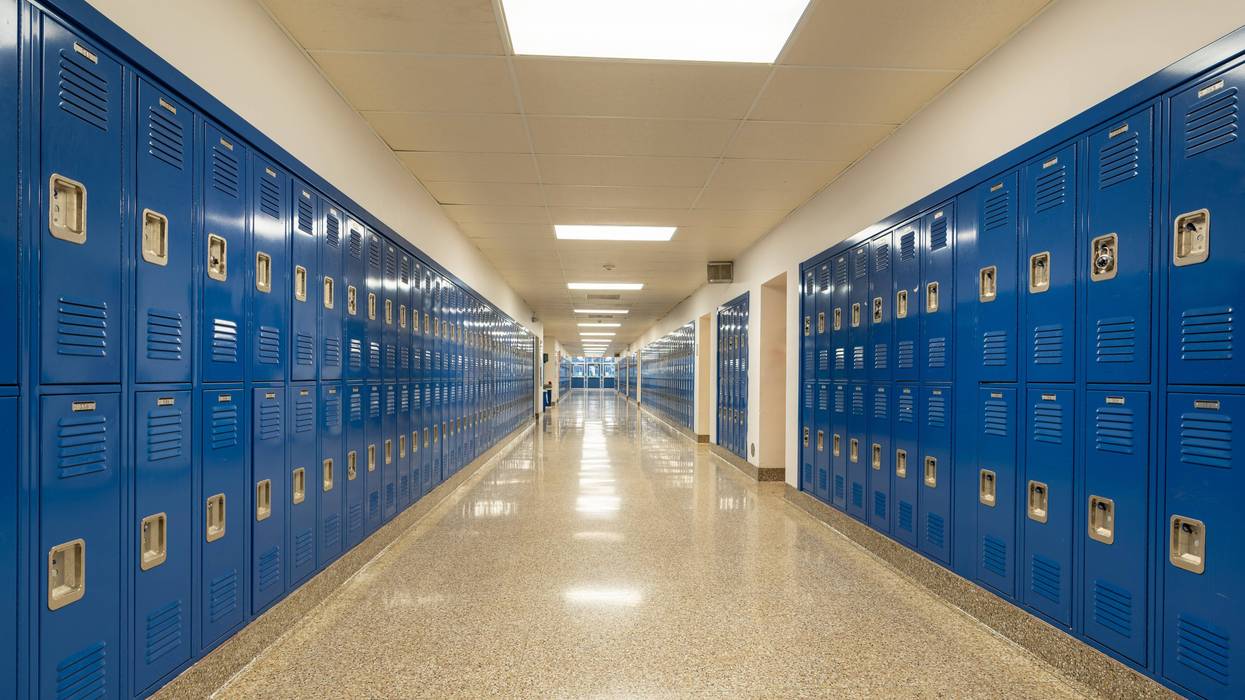 Typical, nondescript USA empty school hallway with royal blue metal lockers along both sides of the hallway. - stock photo