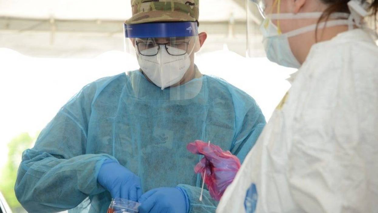 U.S. Air National Guard Senior Airman Manuel Zertuche 185th Air Refueling Wing medical technician works with medical staff in order to administer a COVID-19 test at the Sioux Center, Iowa “TestIowa” test site on May 27, 2020.