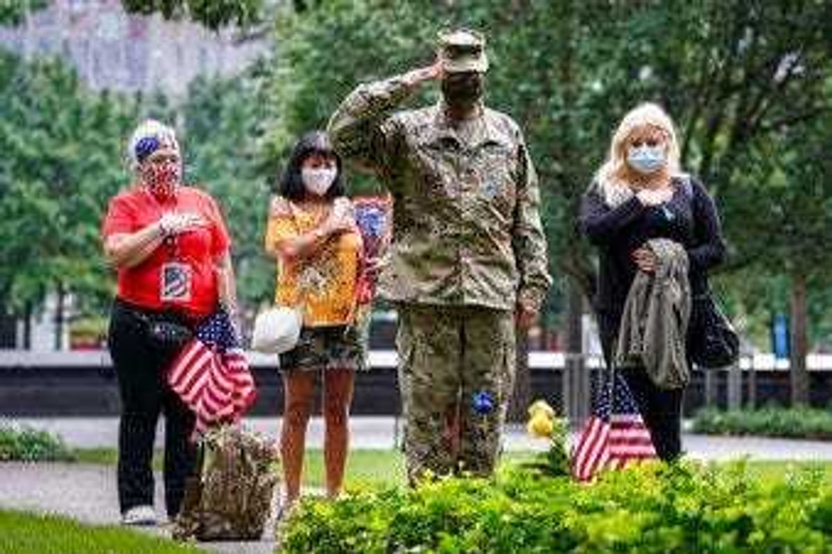 U.S. Army Sgt. Edwin Morales, center right, salutes after placing flowers for fallen FDNY firefighter Ruben D. Correa at the National September 11 Memorial and Museum, Friday, Sept. 11, 2020, in New York. (AP Photo/John Minchillo)
