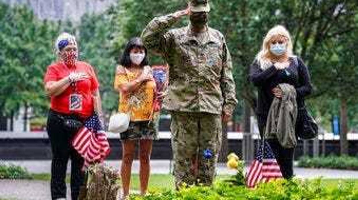 U.S. Army Sgt. Edwin Morales, center right, salutes after placing flowers for fallen FDNY firefighter Ruben D. Correa at the National September 11 Memorial and Museum, Friday, Sept. 11, 2020, in New York. (AP Photo/John Minchillo)