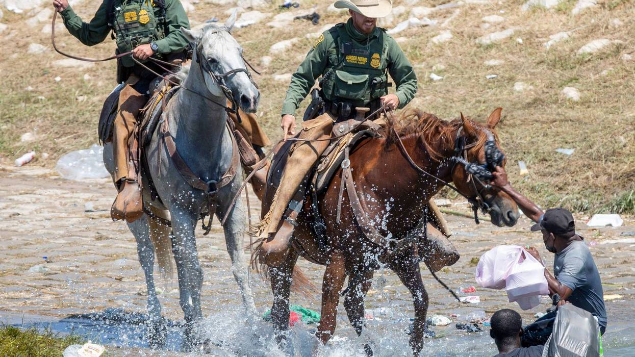 U.S. Border Patrol agents deter Haitians from returning to the U.S. on the bank of the Rio Grande after migrants crossed back to Mexico for food and water.