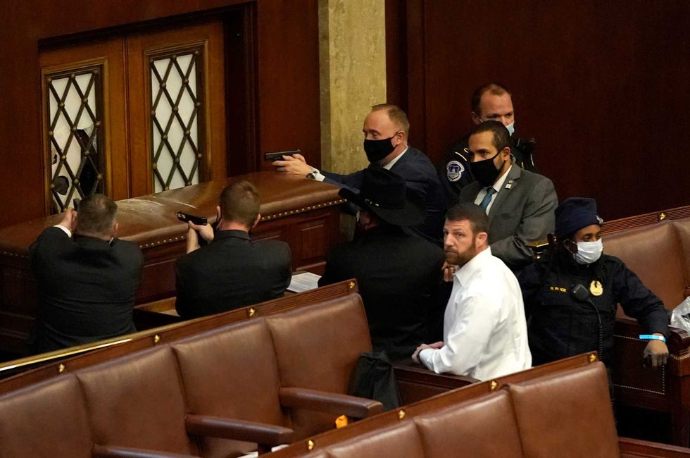 U.S. Capitol police officers point their guns at a door that was vandalized in the House Chamber during a joint session of Congress on January 06, 2021 in Washington, DC. Congress held a joint session today to ratify President-elect Joe Biden