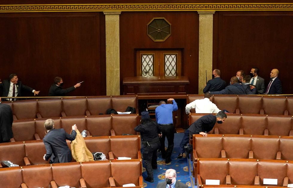 U.S. Capitol police officers point their guns at a door that was vandalized in the House Chamber during a joint session of Congress on January 06, 2021 in Washington, DC. Congress held a joint session today to ratify President-elect Joe Biden