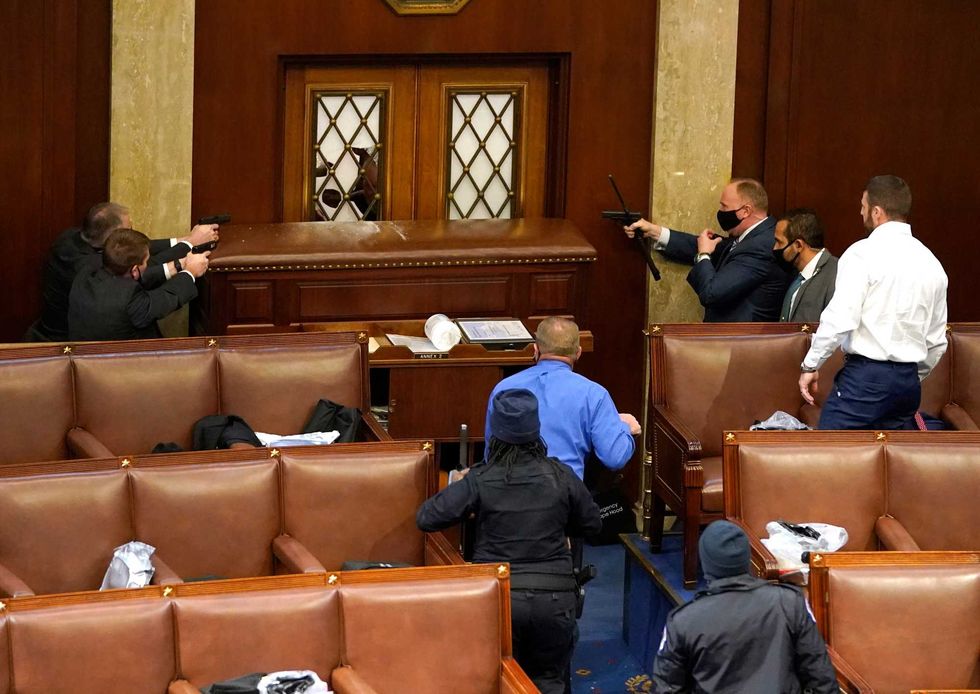 U.S. Capitol police officers point their guns at a door that was vandalized in the House Chamber during a joint session of Congress on January 06, 2021 in Washington, DC. Congress held a joint session today to ratify President-elect Joe Biden