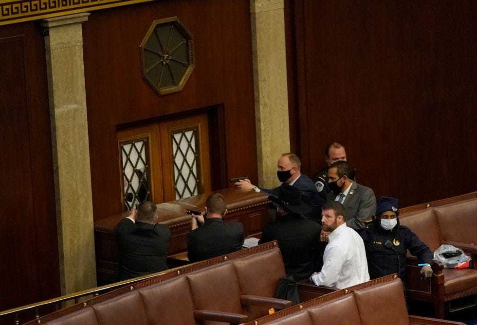 U.S. Capitol police officers point their guns at a door that was vandalized in the House Chamber during a joint session of Congress on January 06, 2021 in Washington, DC.