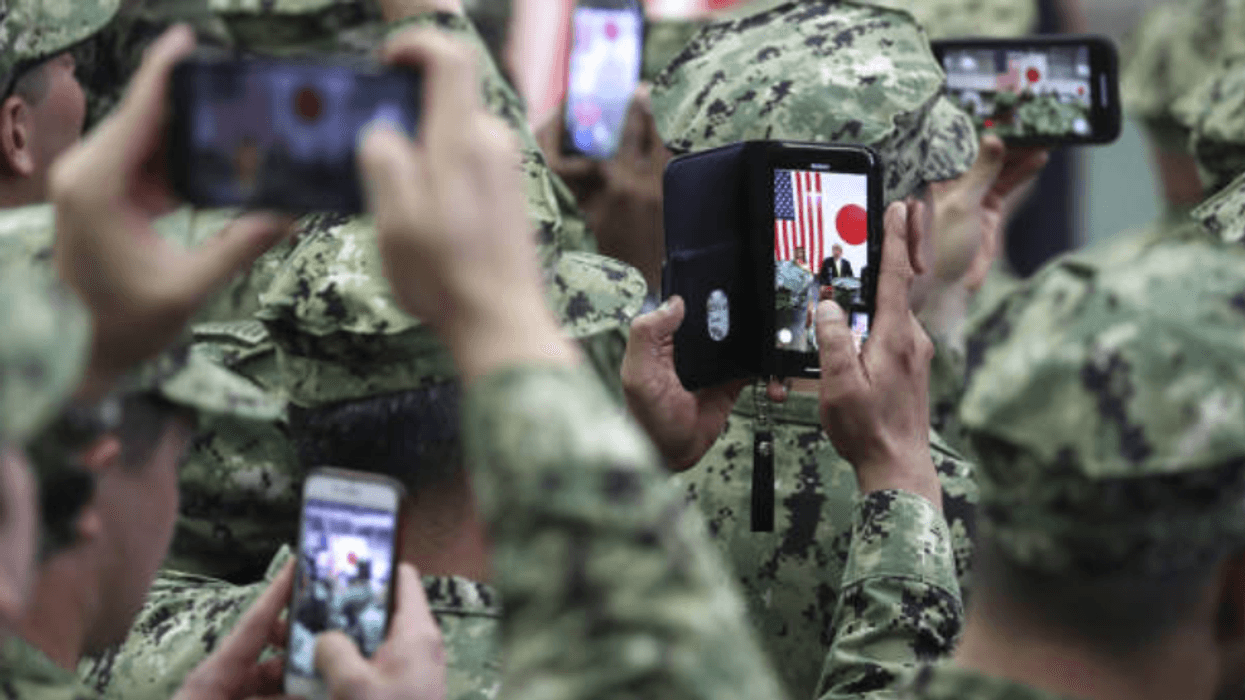 U.S. military personnel use smartphones to take photographs of U.S. President Donald Trump