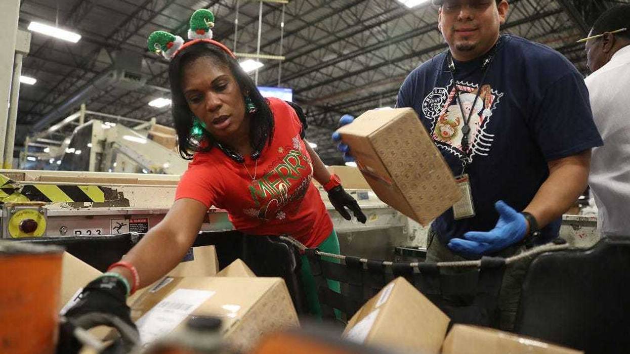 U.S. Postal service mail handlers Barbara Lynn and Daniel Diaz (R) sort boxes at the U.S. Postal service's Royal Palm Processing and Distribution Center on December 4, 2017 in Opa Locka, Florida.
