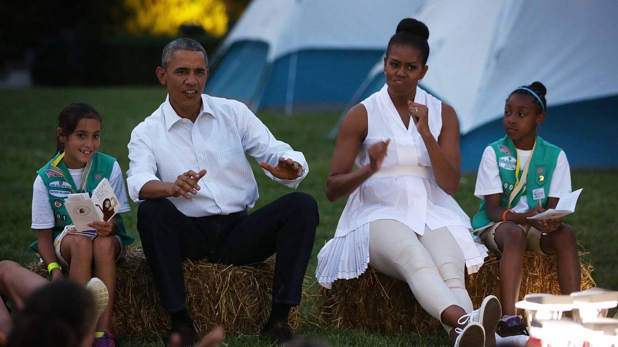 U.S. President Barack Obama (2nd L) and first lady Michelle Obama (3rd L), flanked by Daphnye Shell (L) of Peggs, Oklahoma, and Kennedi Pridget (R) of Maryland, participate in a campfire songs session with fourth-grade Girl Scouts during the first-ever White House Campout June 30, 2015 at South Lawn of the White House in Washington, DC. The first lady hosted the event, as part of her Let's Move! Outside initiative, for Girl Scouts to participate in activities to earn their Camper Badge, and to celebrate the release of the new Girls' Choice Outdoor badges