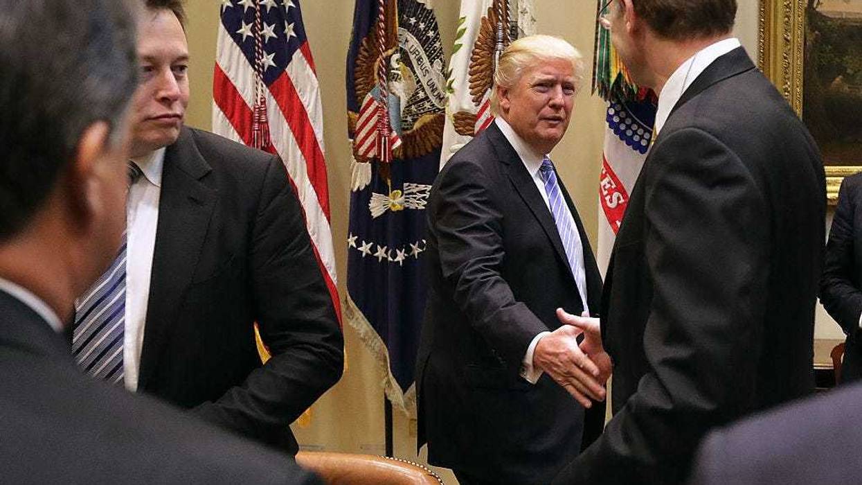 U.S. President Donald Trump (C) greets Wendell Weeks (R) of Corning, Elon Musk of SpaceX (L) and other other business leaders as he arrives for a meeting in the Roosevelt Room at the White House January 23, 2017 in Washington, DC