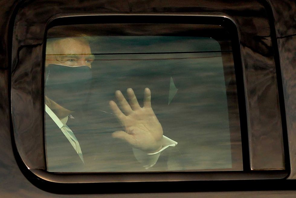 U.S. President Donald Trump waves to his supports from a motorcade outside Walter Reed Medical Center during his treatment of COVID-19 in Bethesda, Maryland on October 4, 2020.