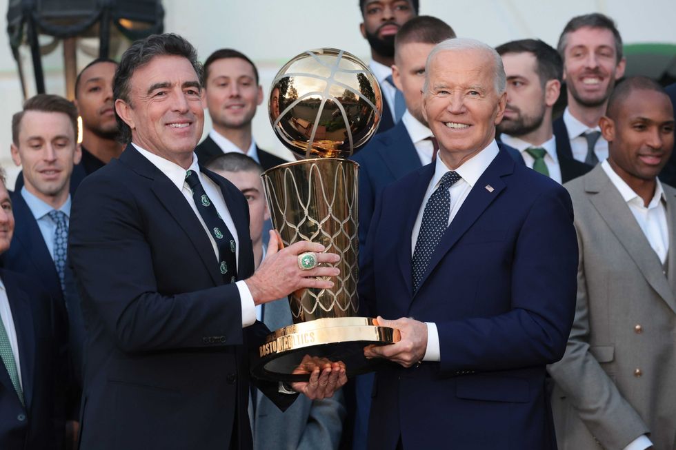 U.S. President Joe Biden and Boston Celtics owner Wyc Grousbeck (L) hold up the NBA Championship trophy as Biden welcomed the 2024 NBA Champion Boston Celtics to the White House November 21, 2024 in Washington, DC.