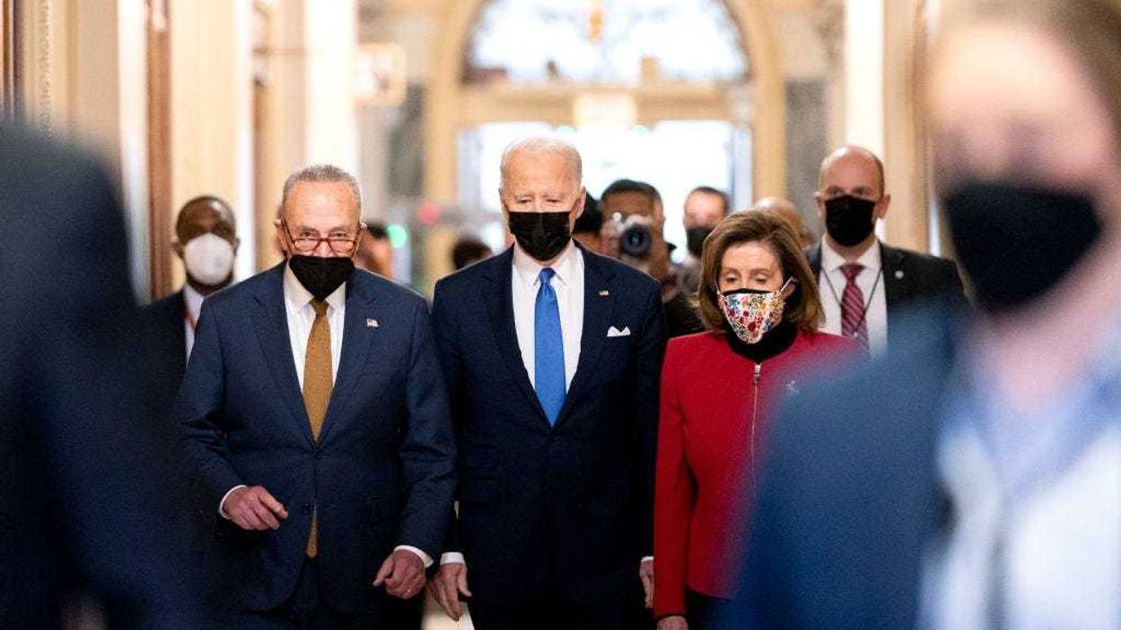 U.S. President Joe Biden, center, joined by Senate Majority Leader Chuck Schumer, (D-NY), left, and U.S. House Speaker Nancy Pelosi (D-CA), walks through the Hall of Columns