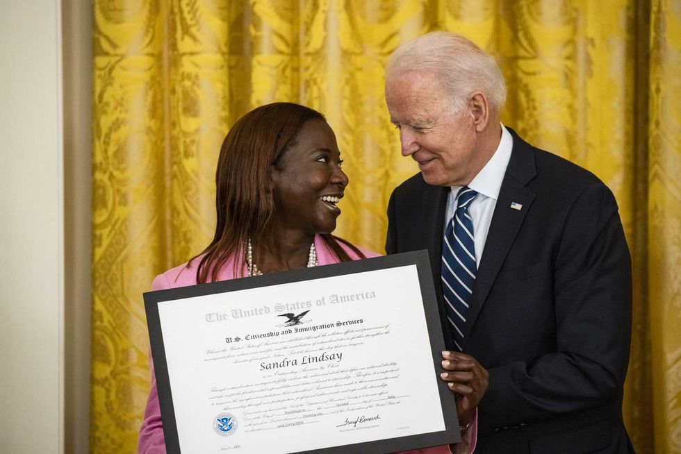 U.S. President Joe Biden presents Sandra Lindsay, a naturalized American Citizen and nurse who was first to receive the Covid-19 vaccine outside of trials, with the Outstanding American by Choice Award from the U.S. Citizen and Immigration Services during a naturalization ceremony in the East Room of the White House in Washington, D.C., U.S., on Friday, July 2, 2021. The ceremony is to welcome citizens to the United States ahead of Independence Day.