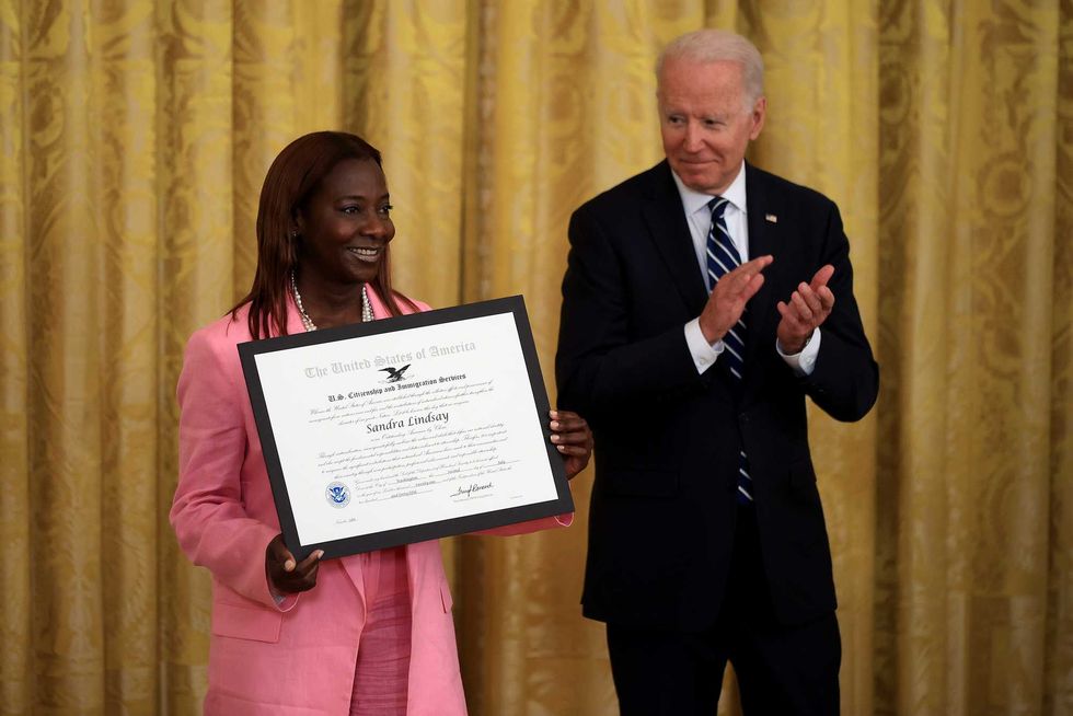 U.S. President Joe Biden presents Sandra Lindsay, a naturalized American Citizen and nurse who was first to receive the Covid-19 vaccine outside of trials, with the Outstanding American by Choice Award from the U.S. Citizen and Immigration Services during a naturalization ceremony in the East Room of the White House in Washington, D.C., U.S., on Friday, July 2, 2021. The ceremony is to welcome citizens to the United States ahead of Independence Day.