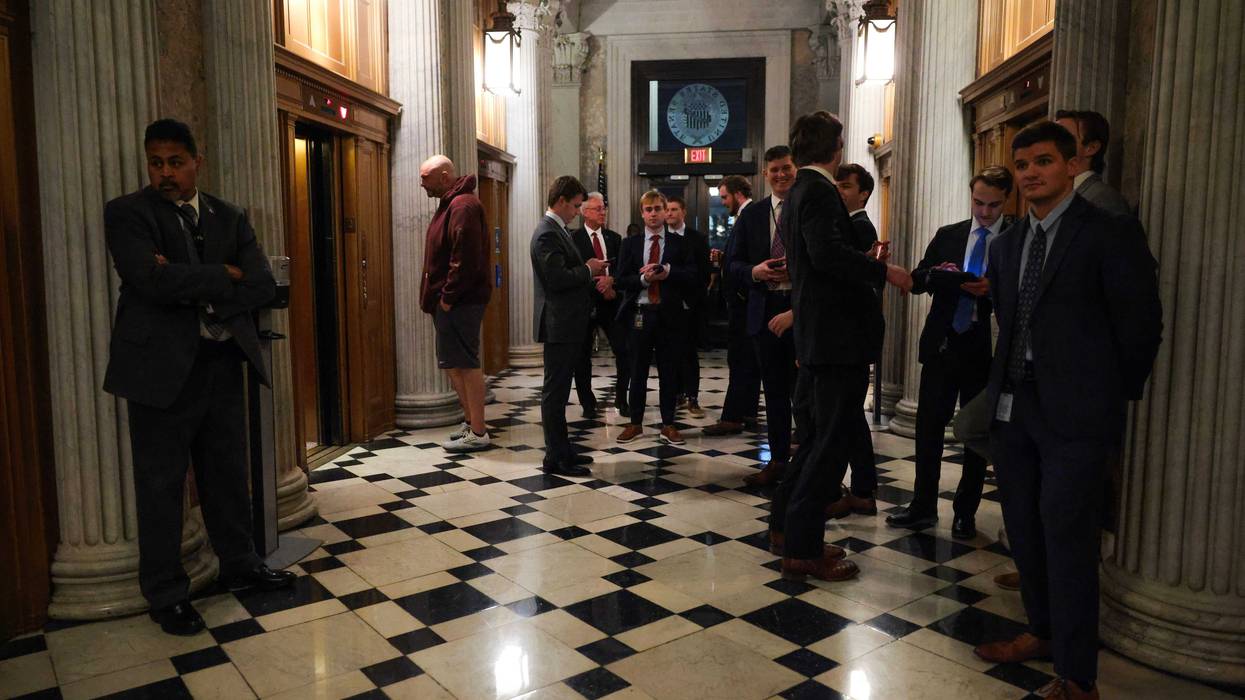 U.S. Sen. John Fetterman (D-PA) (L) waits for an elevator with staffers outside the Senate Chambers during a Senate "vote-a-rama" on February 20, 2025 in Washington, DC. The Senate is holding an all-night marathon vote, referred to as a "vote-a-rama", as Republicans look to pass their GOP budget resolution.