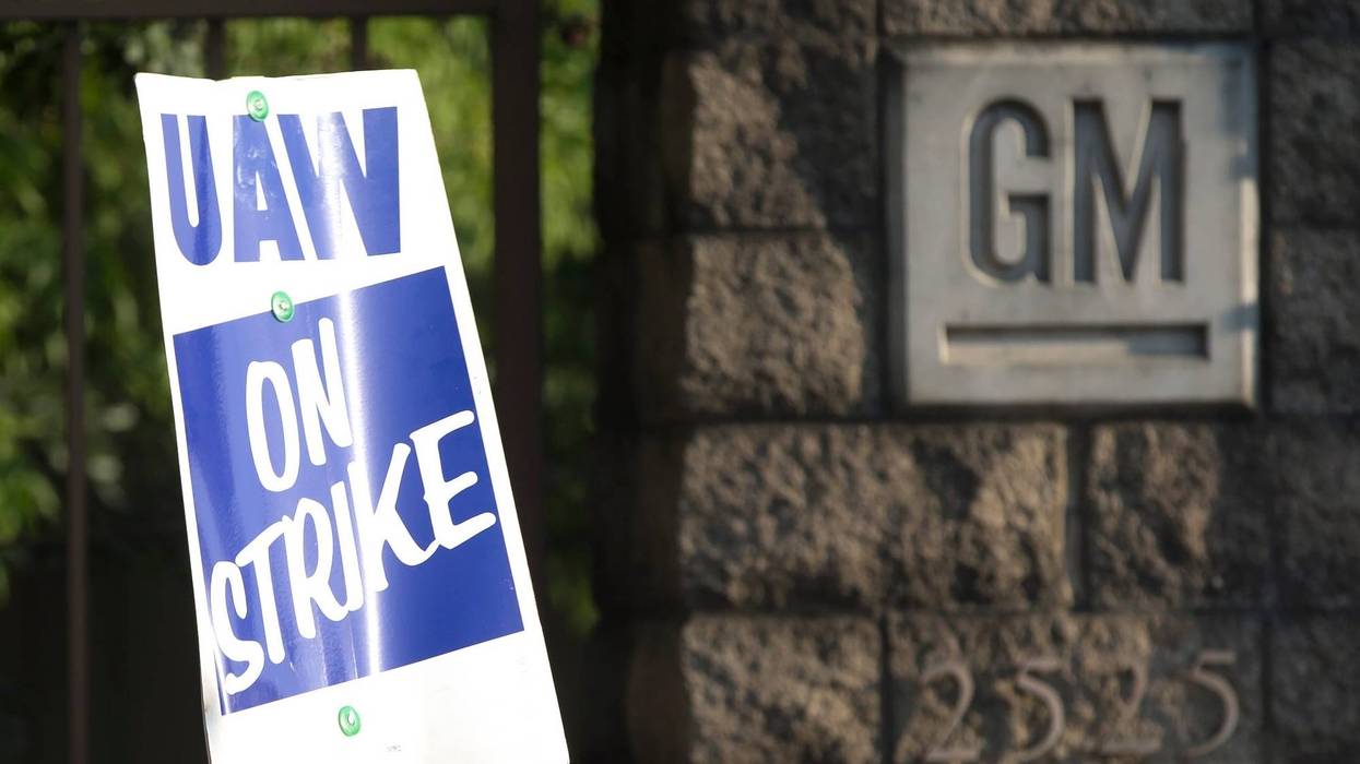 UAW strike sign and GM logo
