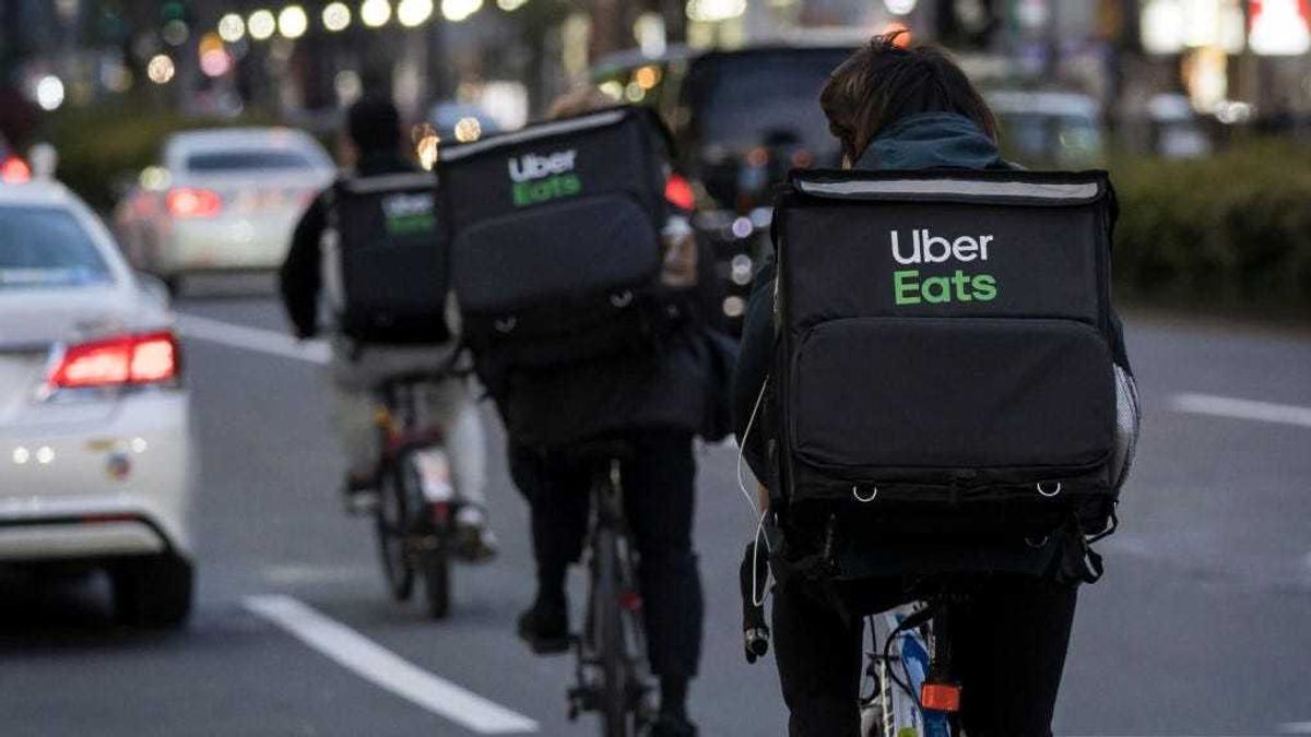 Uber Eats delivery men ride bicycles through the Kabukicho entertainment area on April 11, 2020 in Tokyo, Japan.