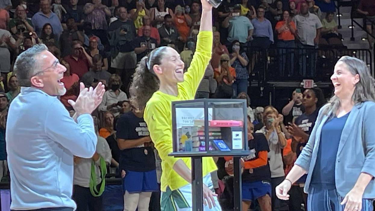 UConn basketball legend Sue Bird (at center) accepts a rack of books and a bottle of wine from the Connecticut Sun before her final game in Connecticut, at Mohegan Sun Arena, 7/28/22