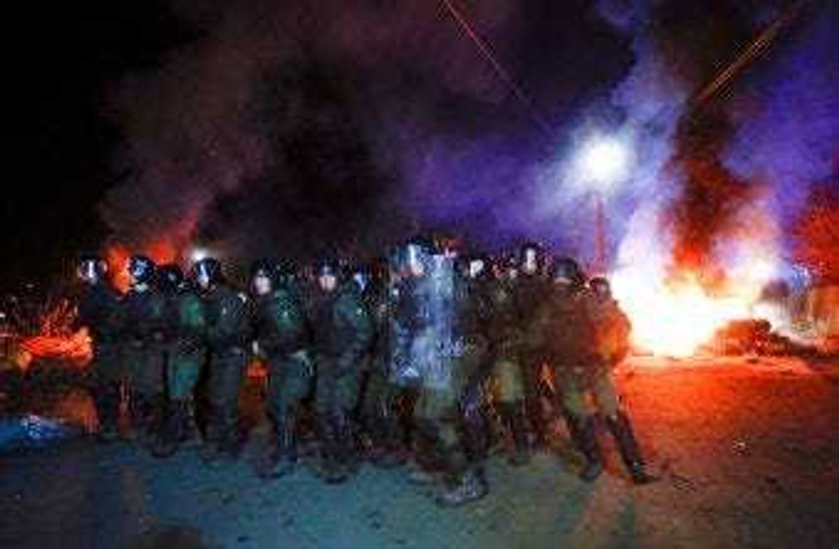 Ukrainian riot police prepare to push back protesters, who planned to stop buses carrying passengers evacuated from the Chinese city of Wuhan, outside Novi Sarzhany, Ukraine, Thursday, Feb. 20, 2020. (AP Photo/Efrem Lukatsky)