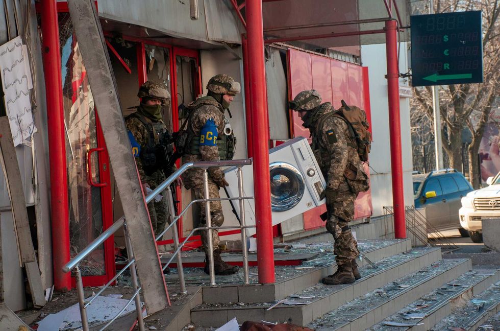 Ukrainian servicemen carry a washing machine as they help to relocate goods from a destroyed by shelling market in Kharkiv, Ukraine.