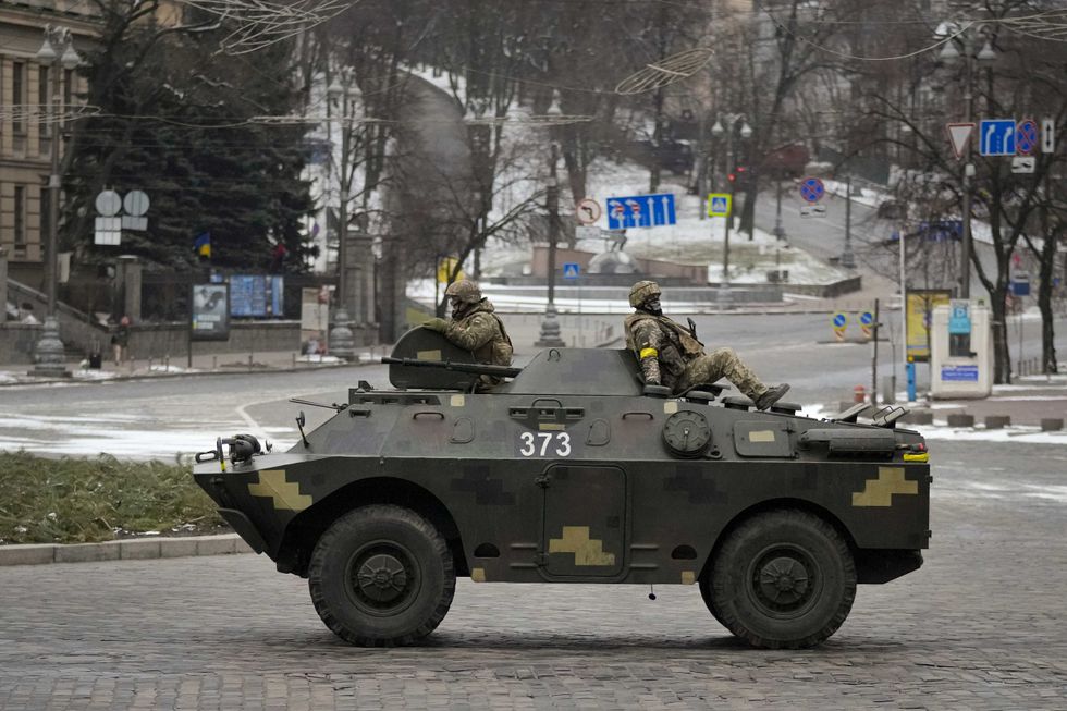 Ukrainian servicemen ride on top of an armored personnel carrier speeding down a deserted boulevard during an air raid alarm, in Kyiv, Ukraine, Tuesday, March 1, 2022