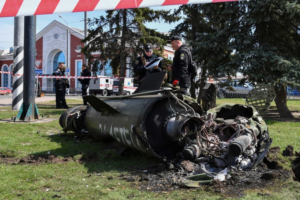Ukrainian servicemen stand next to a fragment of a Tochka-U missile with a writing in Russian "For children" , on a grass after Russian shelling at the railway station in Kramatorsk, Ukraine, Friday, April 8, 2022