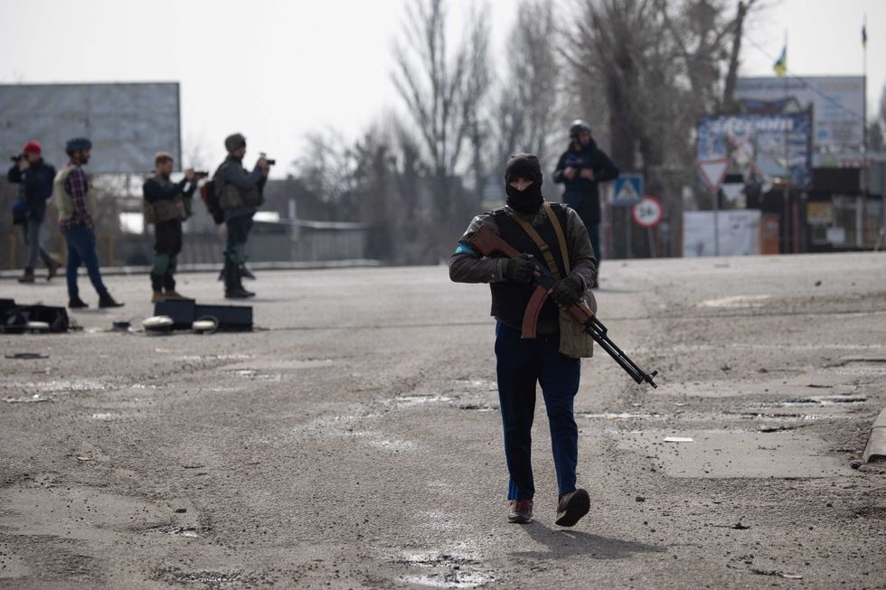 Ukrainian soldiers from the Civil Defense stand next to damage gas station and buildings after Russian Shelling in Stoyanka, near Kiev, on March 31, 2022