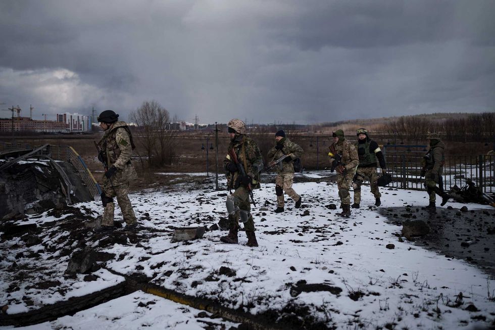 Ukrainian soldiers walk on a destroyed bridge in Irpin, on the outskirts of Kyiv, Ukraine, Tuesday, March 8, 2022