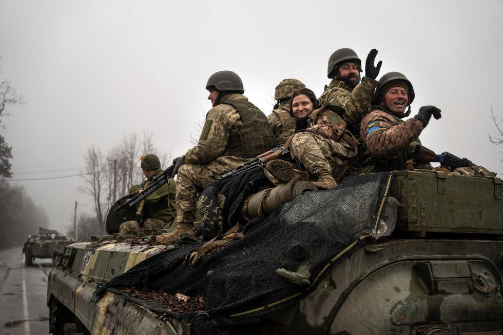 Ukrainian soldiers wave to reporters during a military sweep to search for possible remnants of Russian troops after their withdrawal from villages in the outskirts of Kyiv, Ukraine, Friday, April 1, 2022