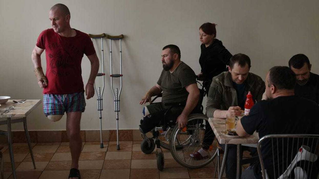 Ukrainian soldiers who have lost limbs while fighting against the Russians in eastern Ukraine, including Ivan Nekrasov (C), 35, who drove a Gvozdika self-propelled howitzer and lost both legs when it hit a landmine, arrive for lunch at the cafeteria at the rehabilitation center that is their home for now on February 25, 2023 in Lviv, Ukraine.