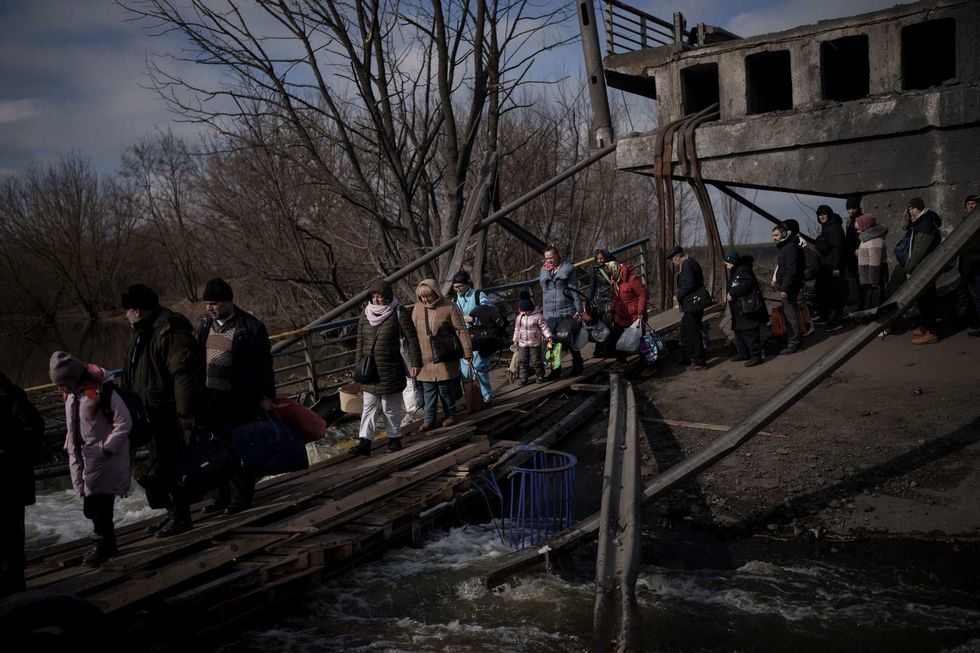 Ukrainians cross an improvised path under a destroyed bridge while fleeing Irpin, on the outskirts of Kyiv, Ukraine, Wednesday, March 9, 2022