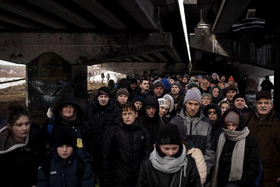 Ukrainians crowd under a destroyed bridge as they try to flee crossing the Irpin river in the outskirts of Kyiv, Ukraine, Tuesday, March 8, 2022