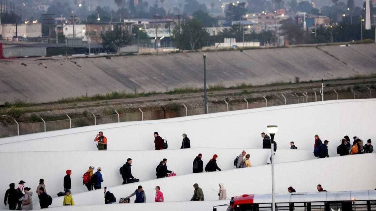 Ukrainians seeking asylum walk at the El Chaparral port of entry before sunrise on their way to enter the United States on April 7, 2022 in Tijuana, Mexico.