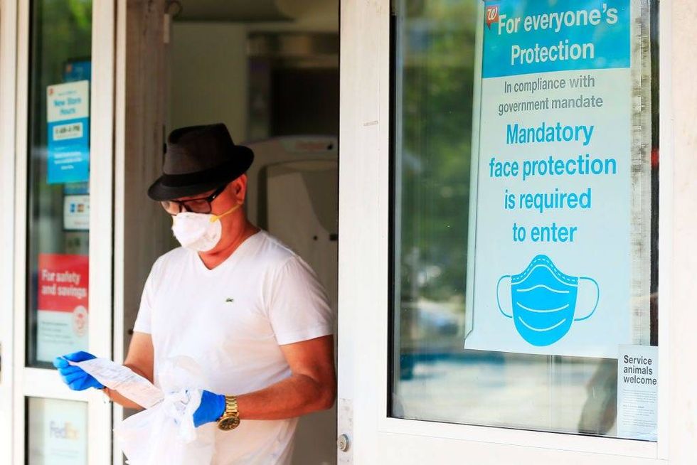 Un cliente en mascarilla sale de una farmacia Walgreens