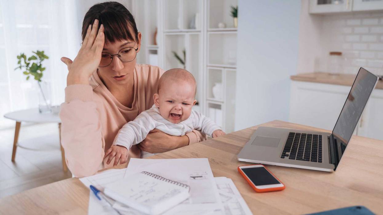 Unhappy frustrated single mother with crying children trying to work at home or solve family financial troubles, tired of balancing motherhood and work, doesn't have money to pay domestic bills
