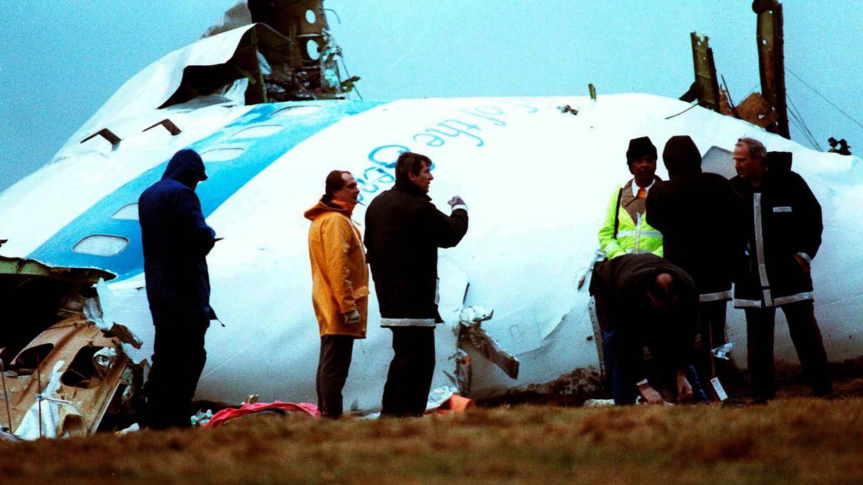 Unidentified crash investigators inspect the nose section of the crashed Pan Am flight 103, a Boeing 747 airliner in a field near Lockerbie, Scotland, Dec. 23, 1988.
