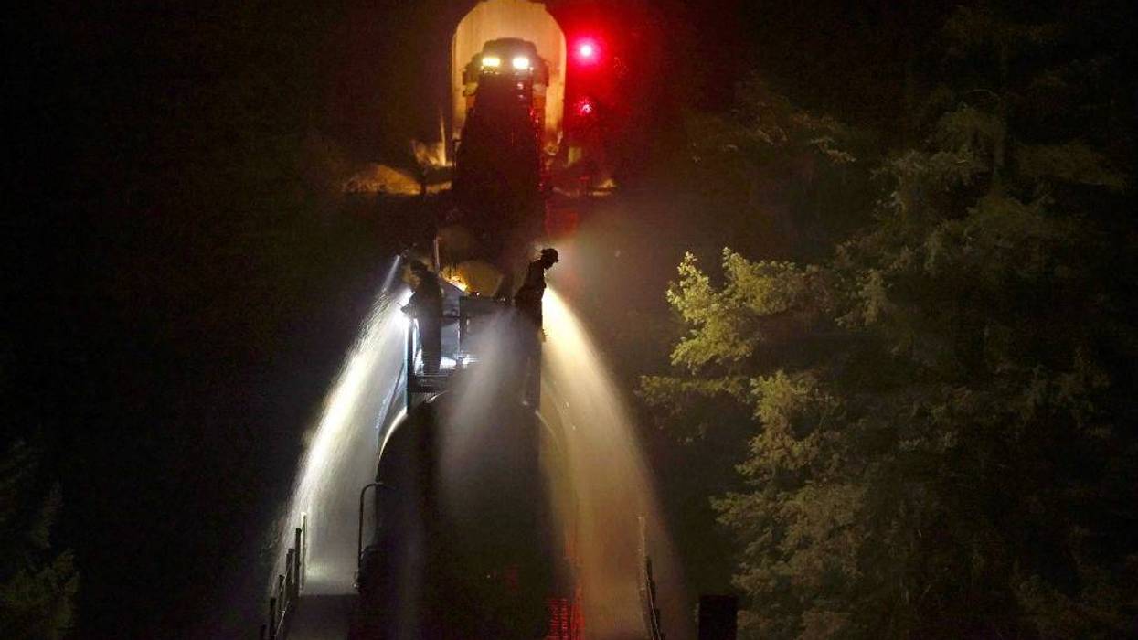 Union Pacific workers spray water along from a train along train tracks as the Dixie Fire burns in the area on July 26, 2021 near Quincy, California.