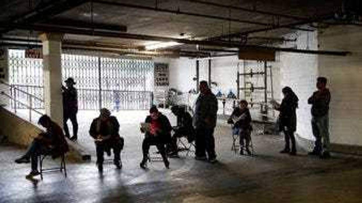Unionized hospitality workers wait in line in a basement garage to apply for unemployment benefits at the Hospitality Training Academy Friday, March 13, 2020, in Los Angeles. (AP Photo/Marcio Jose Sanchez)