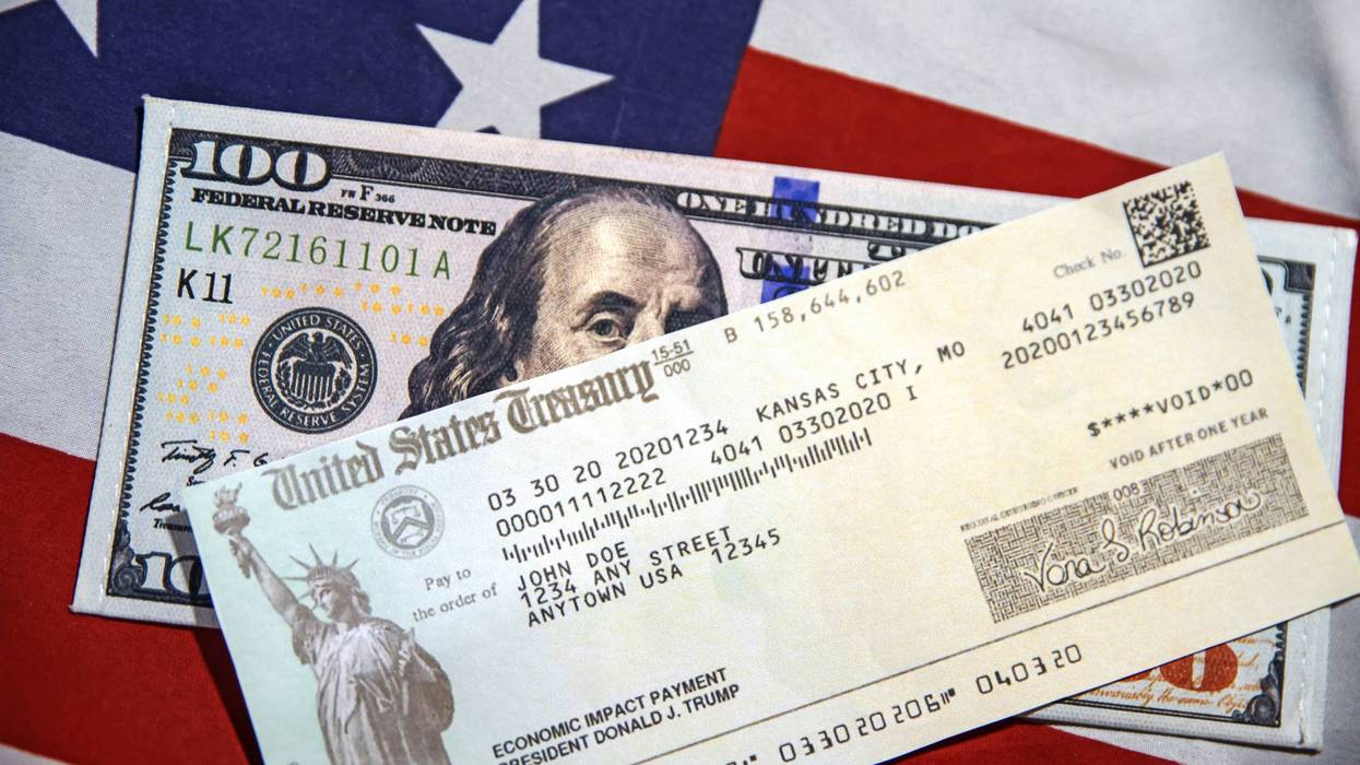 United States Treasury check with 100 dollars bill and American flag in the backdrop. Treasury Check of U.S. close up shot with money