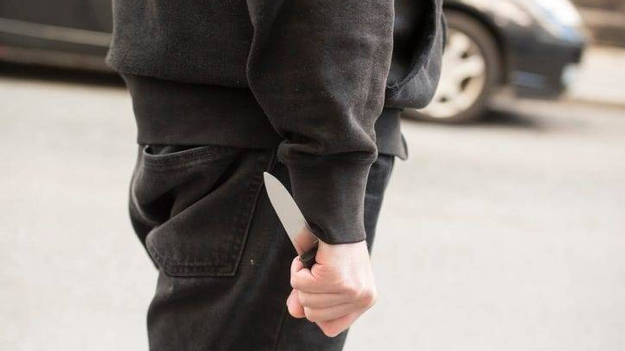 Upper legs and lower torso of a man. His hand is at his side and he is holding a knife.