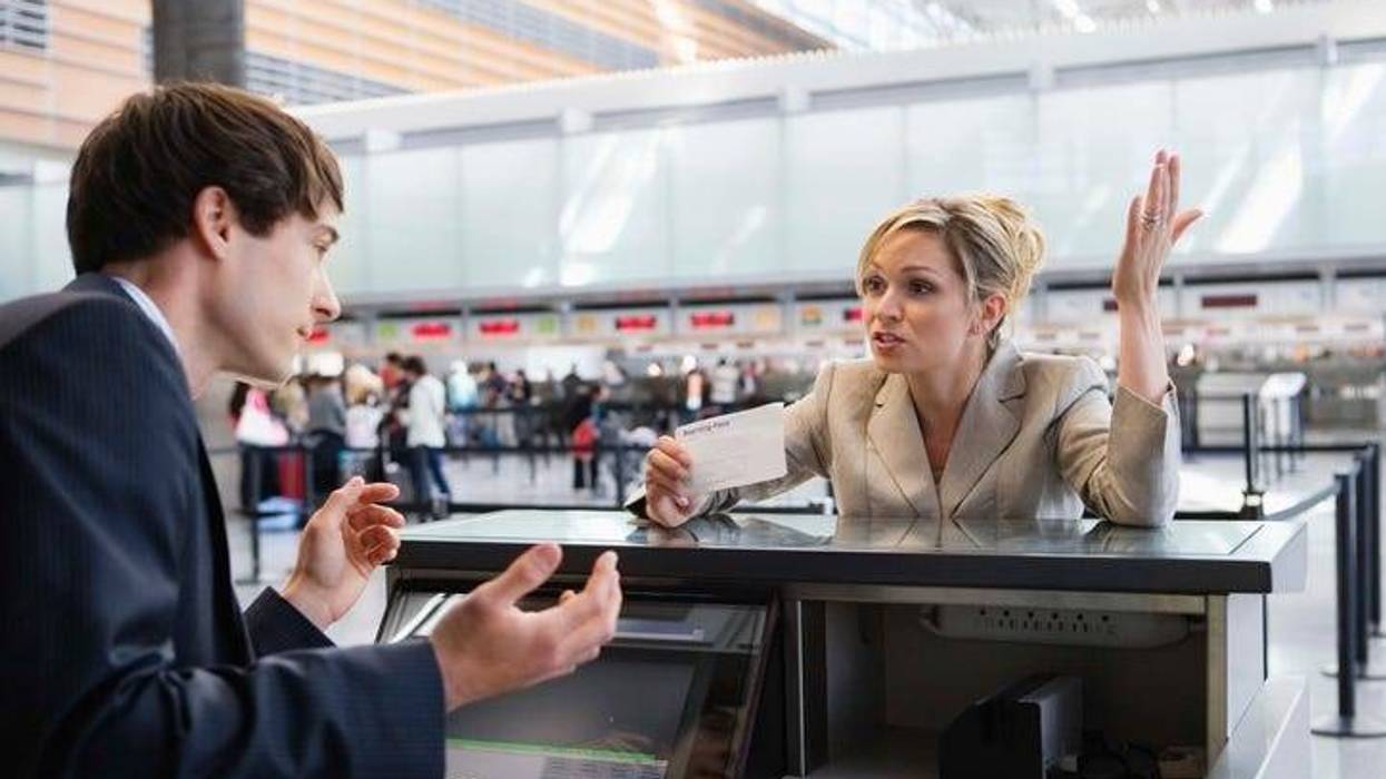 Upset businesswoman checking in at airport ticket counter