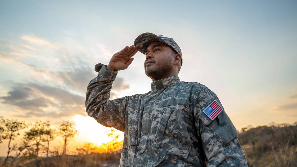 Us Army veteran honors Veterans Day. Man soldier adjusts the US military patch before duty. A US soldier with an American flag patch on his uniform prayers for Memorial Day. Independence Day