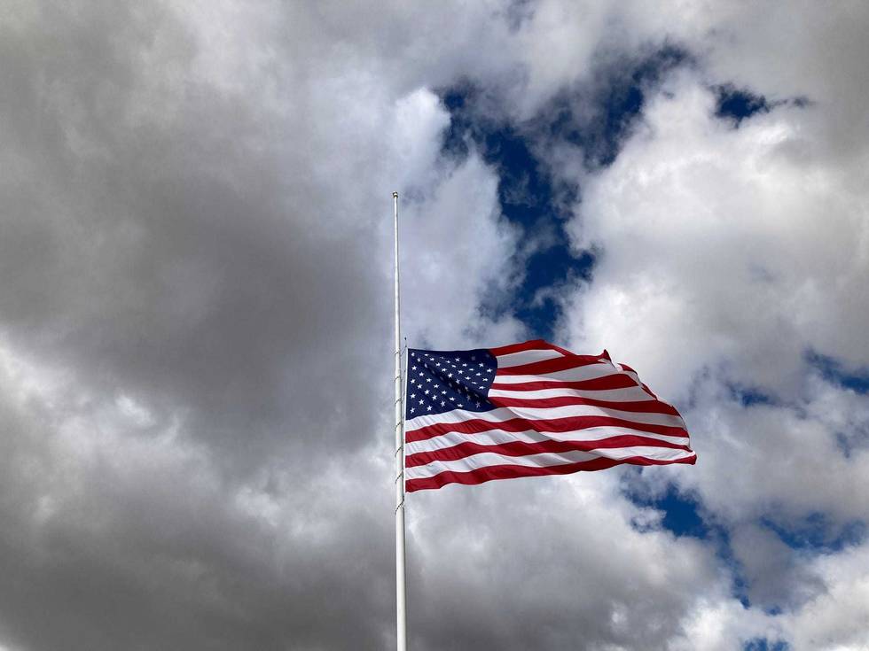 Us Flag At Half Mast Blows in the Wind Under A Dramatic Sky That is Half Gray Clouds and Half Blue