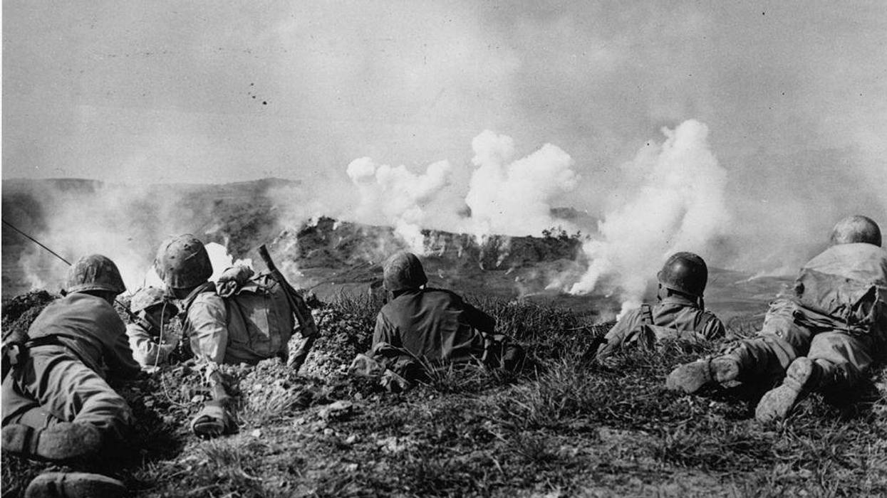 US Marines of the 1st Division wait on the crest of a hill in southern Okinawa, as they watch phosphorous shells explode over Japanese soldiers dug into the hills.