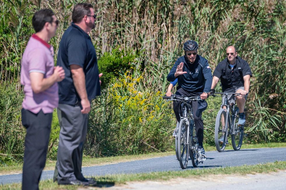 US President Joe Biden(C) rides his bike through Cape Henlopen State Park in Rehoboth Beach, Delaware, on September 19, 2021.