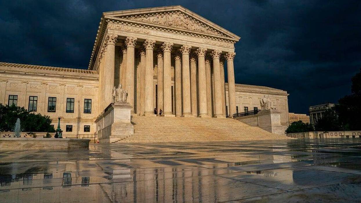 US Supreme Court building under dark, stormy sky, reflecting on wet plaza.