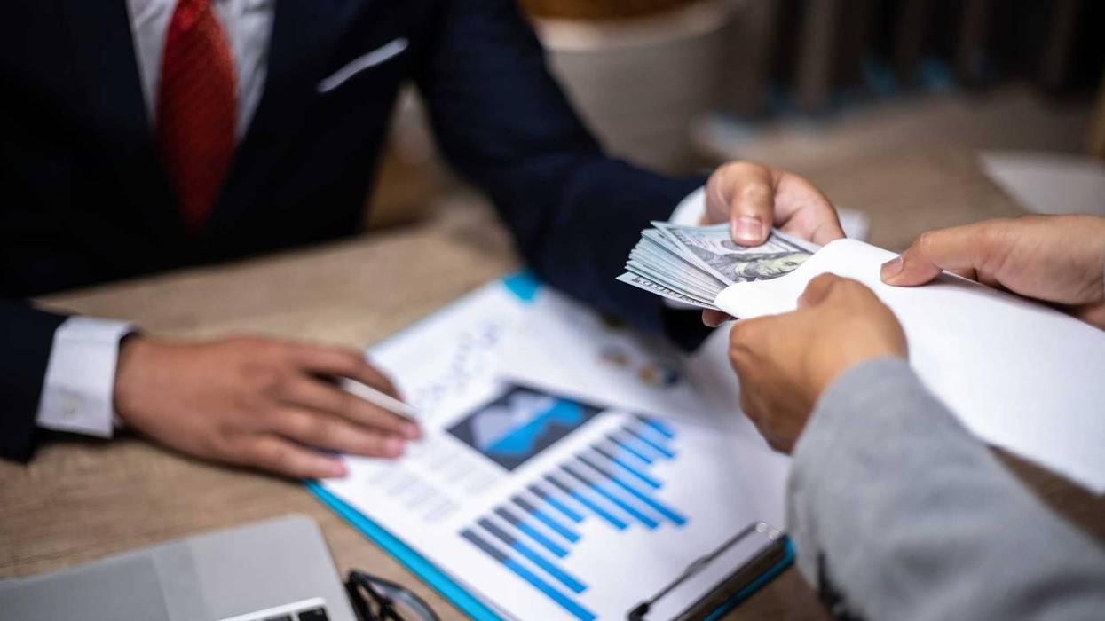 usinessman giving bribe money to partner in a corruption scam