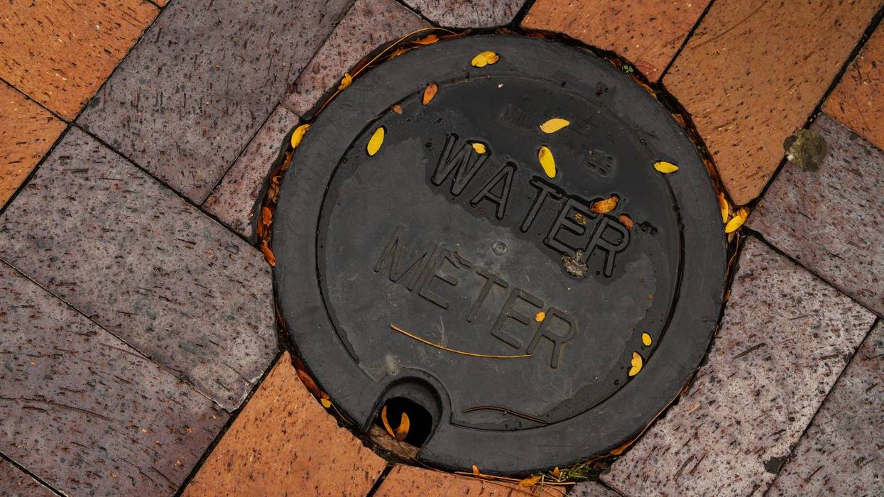 Utility water meter on a brick sidewalk.
